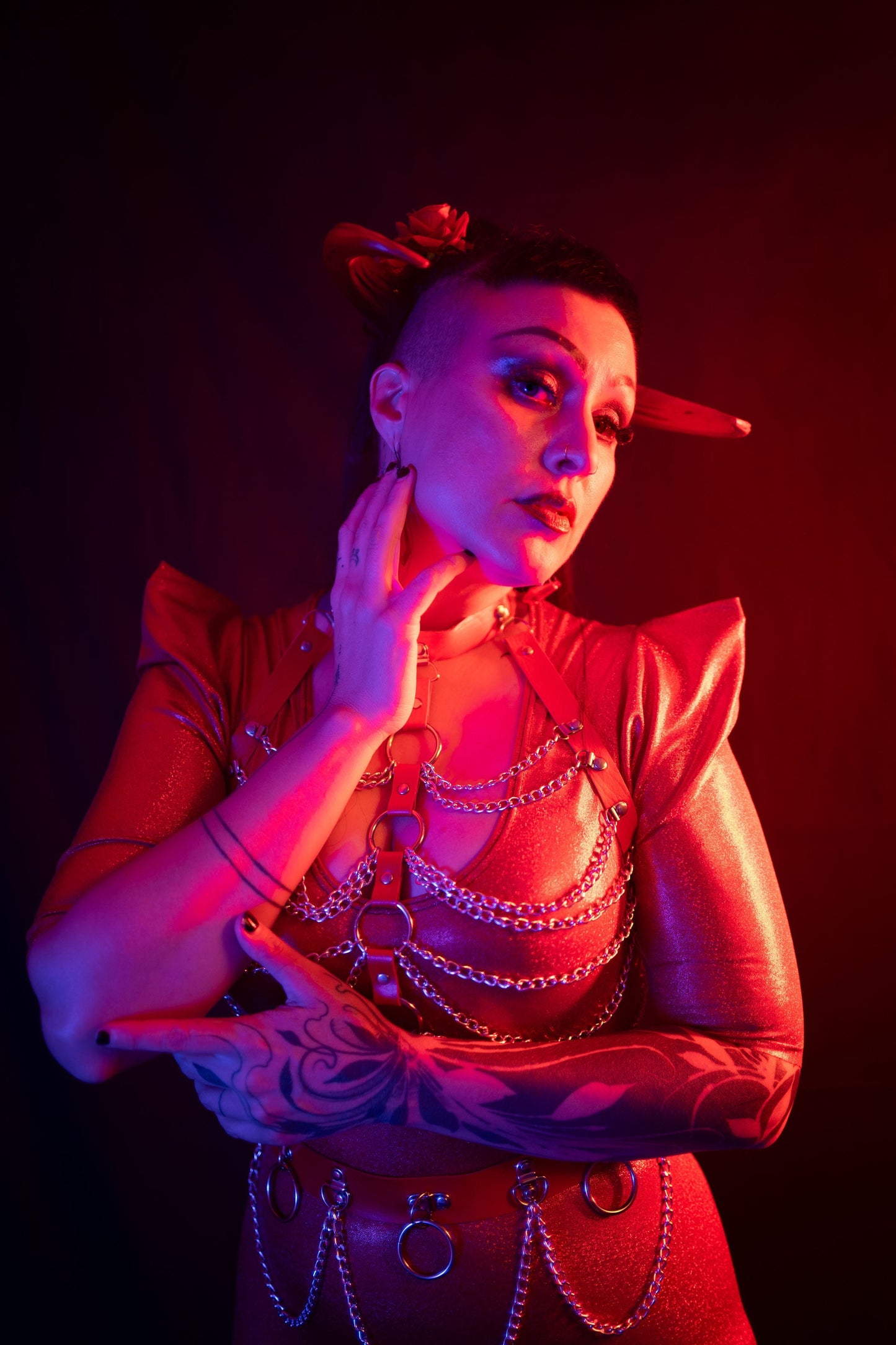 Zoe Sol models Azazel horns by Haus of Brimstone in a glossy red ensemble with harness and chains. Photo by Optic Onslaught.
