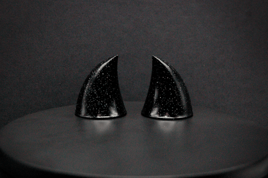 A pair of small black devil horns with a glitter finish.