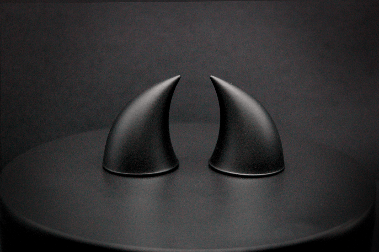 A pair of small black devil horns with a matte finish.