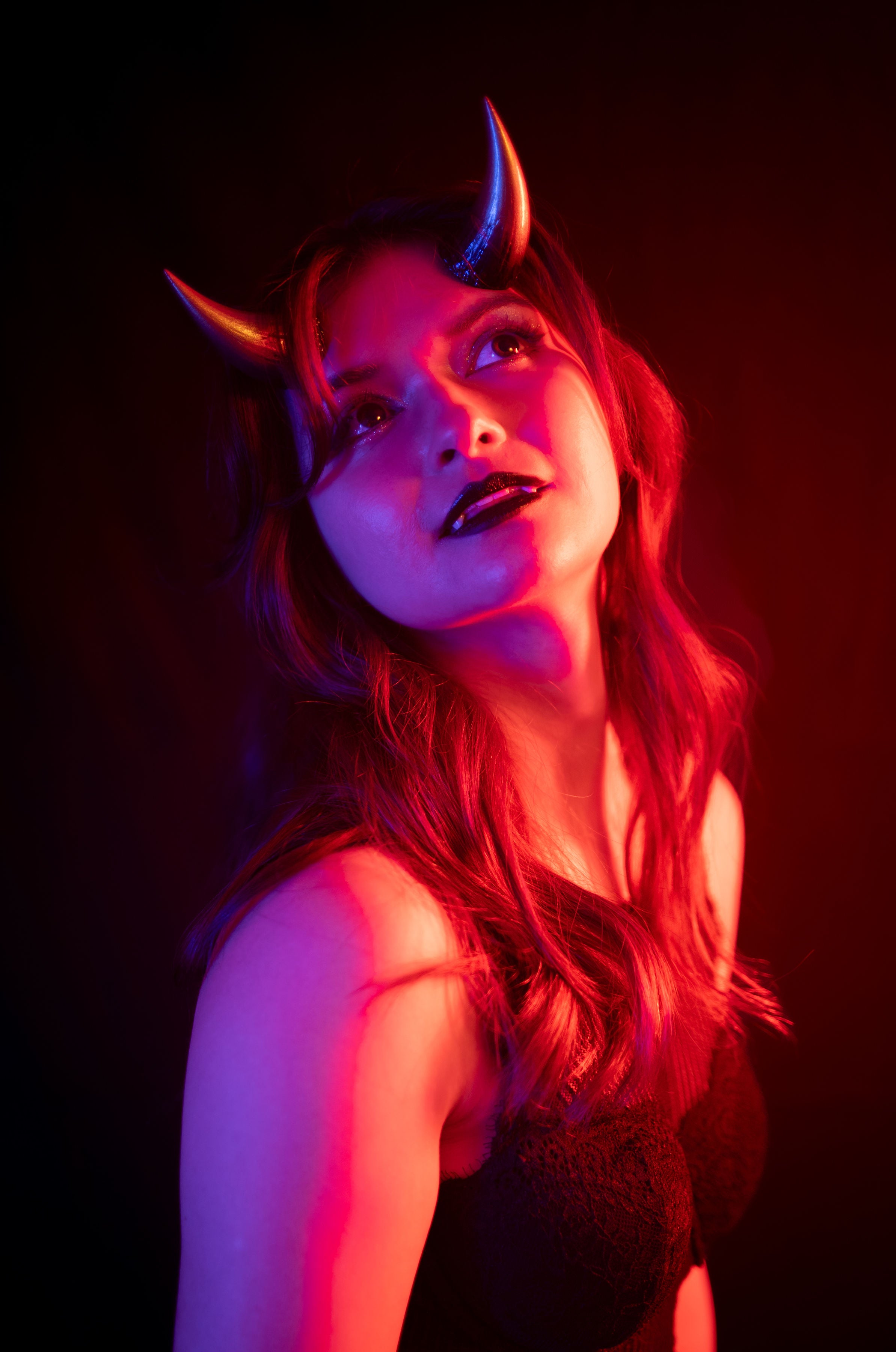 Bambi Bloodmoon models Haus of Brimstone Fiend Horns, wearing fangs and black lipstick, in a photo by Optic Onslaught. 
