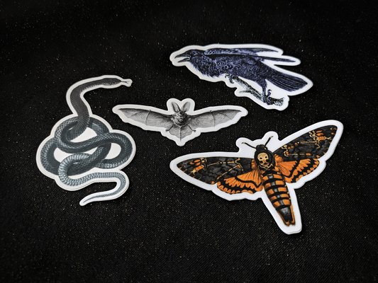 A collection of matte stickers including a snake, bat, crow, and death’s head moth.
