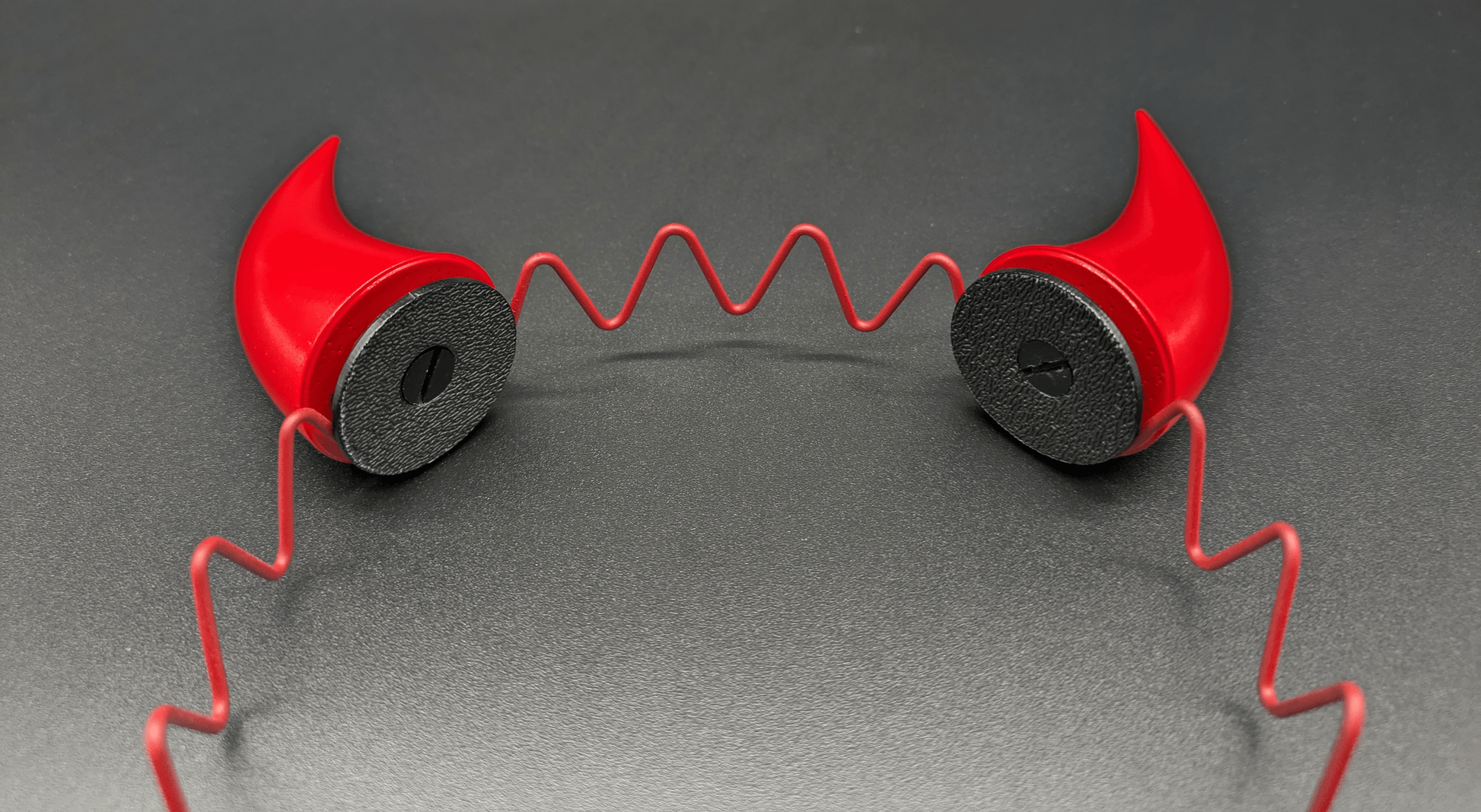 Closeup view of two scarlet red incubus horns attached to a headband.