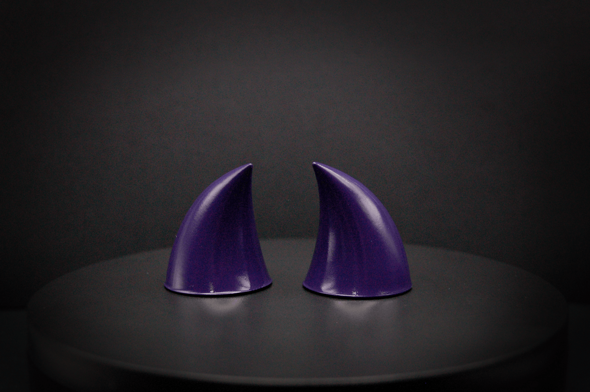 Back view of imp devil horns in belladonna violet, a dark purple with a glossy finish.