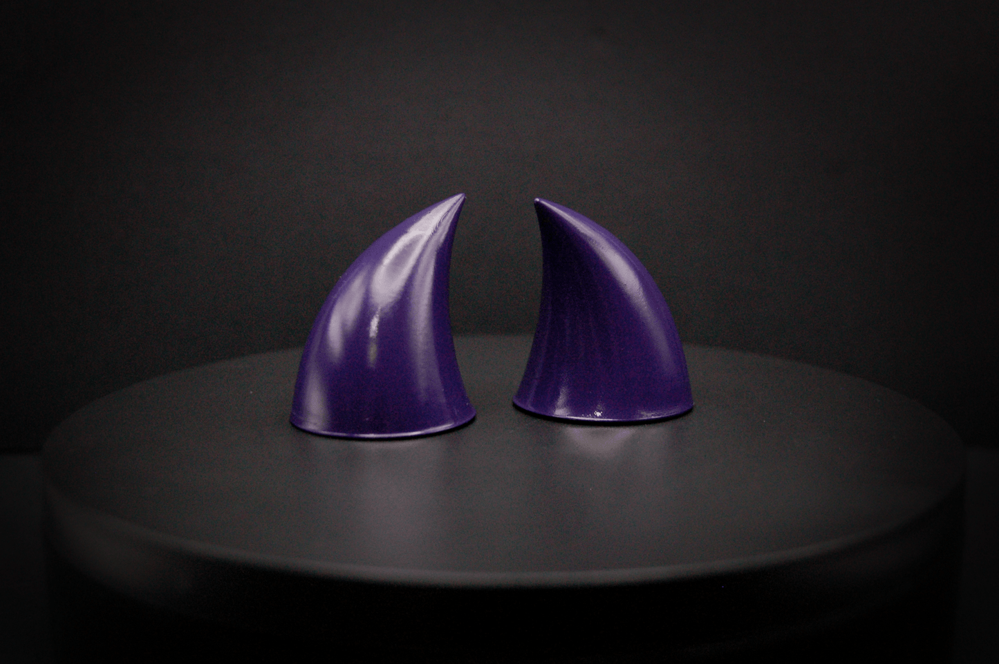 Side view of imp devil horns in belladonna violet, a dark purple with a glossy finish.