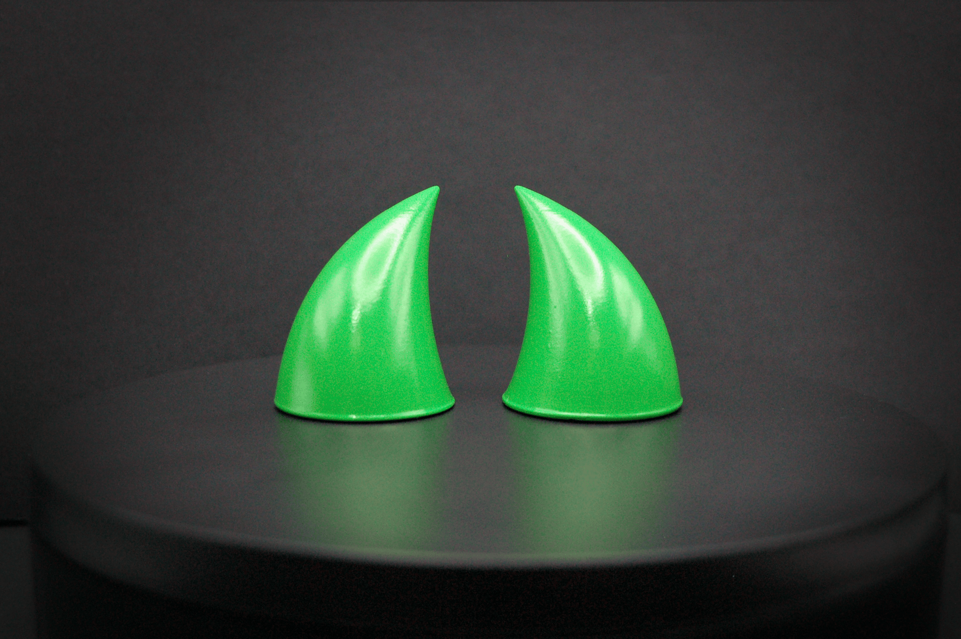 Front view of imp devil horns in goblin green, a bright green with a glossy finish.