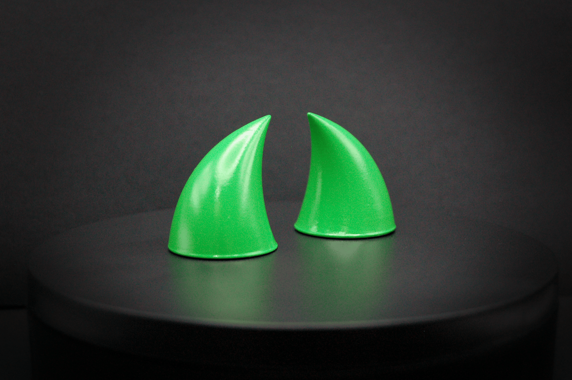 Side view of imp devil horns in goblin green, a bright green with a glossy finish.