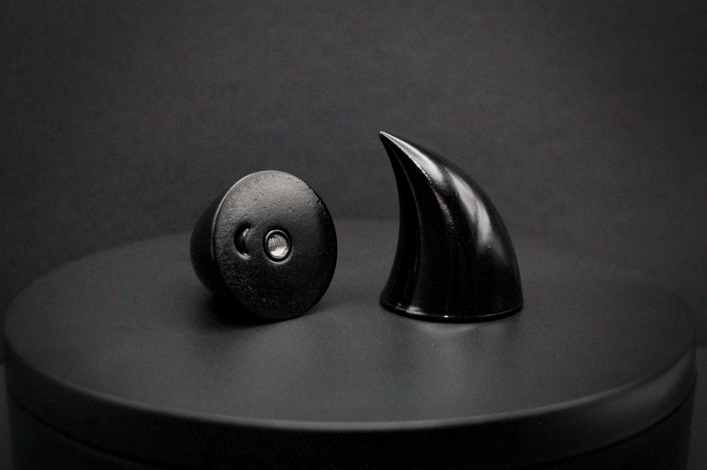 Bottom view of imp devil horns in black with a glossy finish, showing a threaded insert on the base.