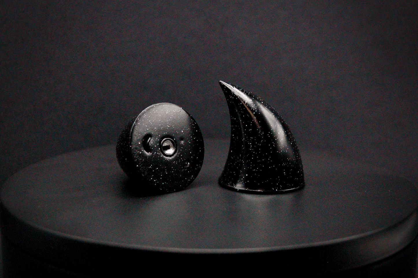A pair of small black devil horns with a glitter finish and threaded insert bottom.