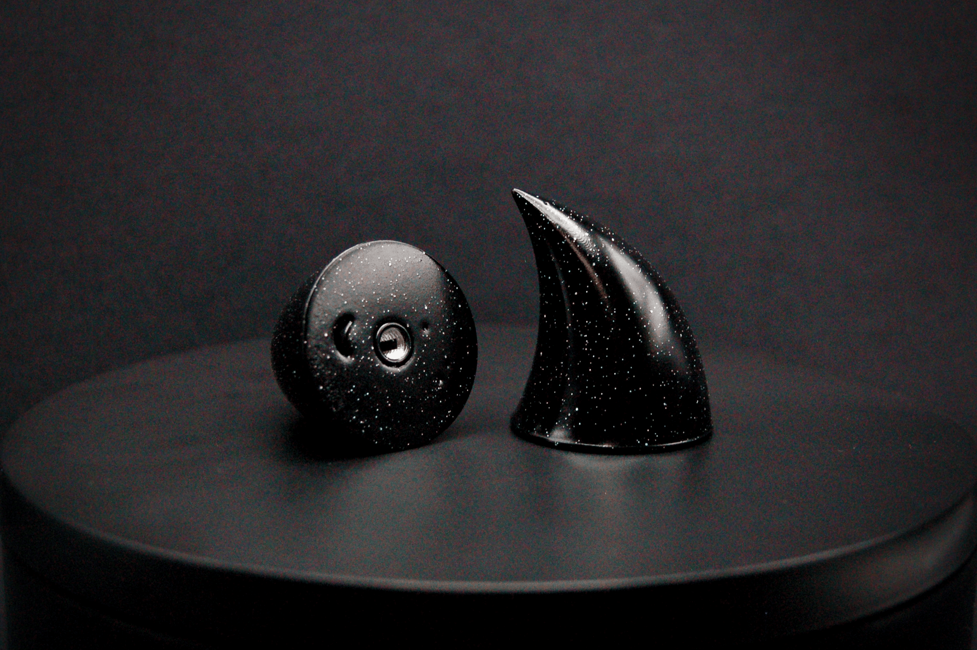 A pair of small black devil horns with a glitter finish and threaded insert bottom.