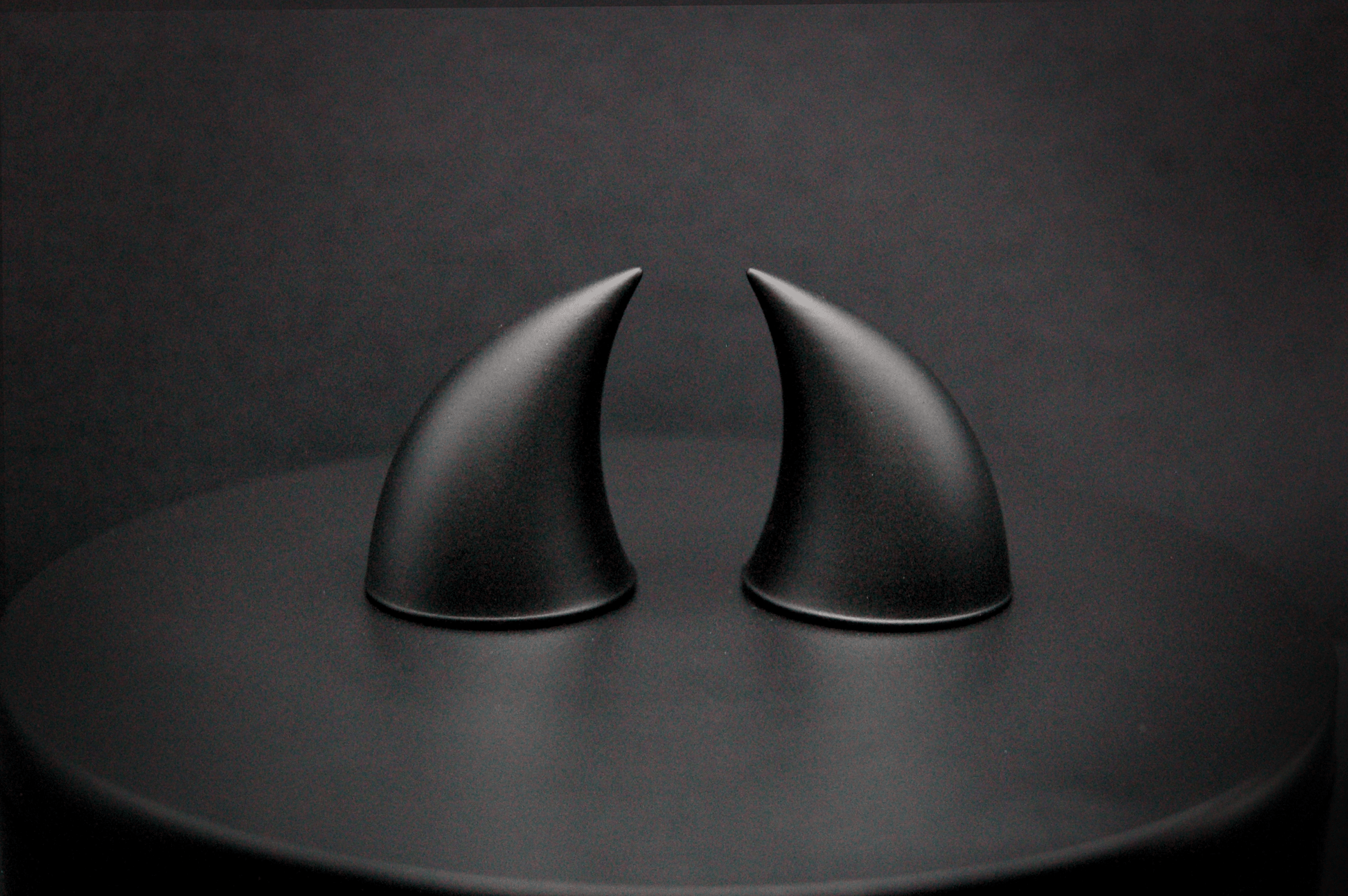 A pair of small black devil horns with a matte finish.