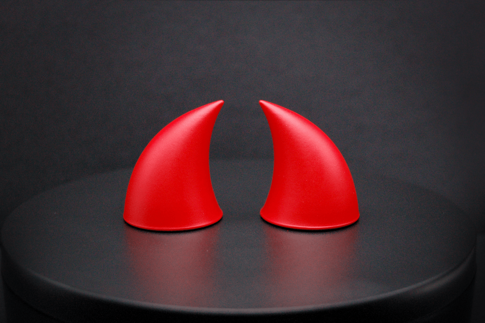 Side view of imp devil horns in scarlet red with a matte finish.