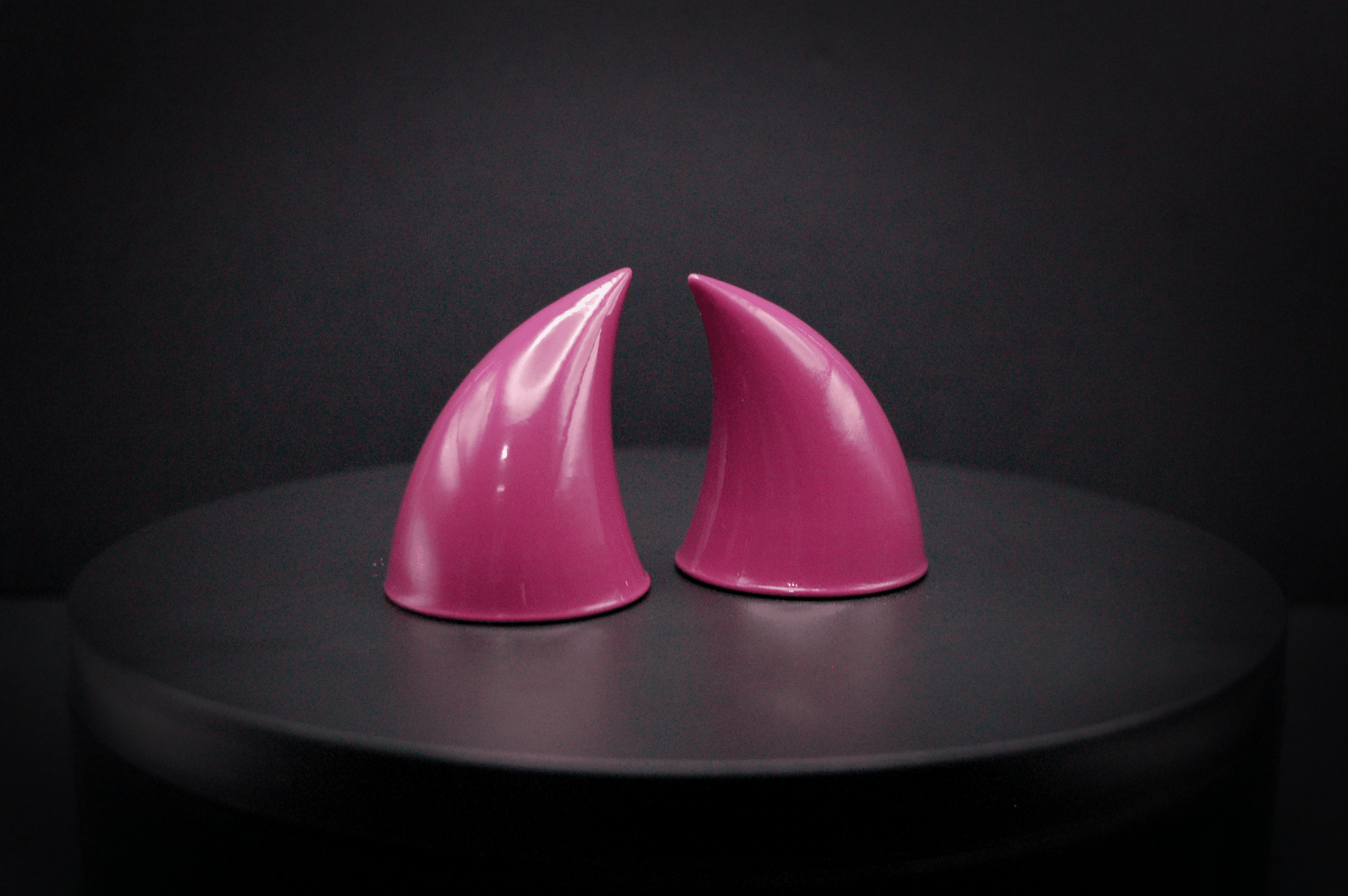 Side view of imp devil horns in deep rose with a glossy finish.