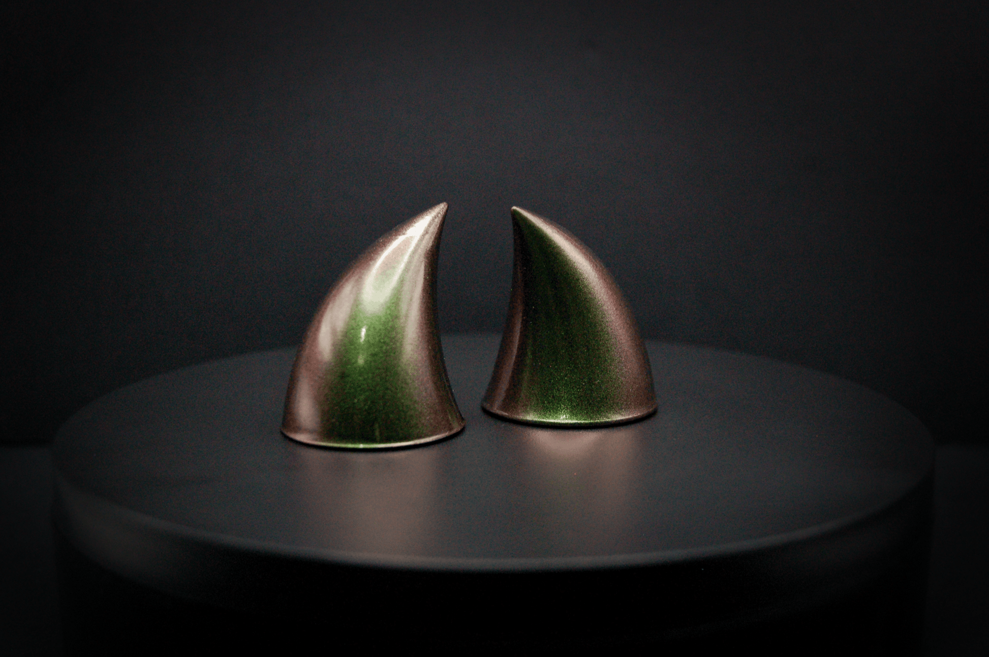 Side view of imp devil horns in metallic coppery green.
