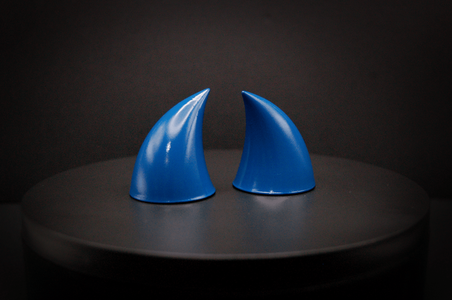 Side view of imp devil horns in storm blue, a deep blue with a glossy finish.