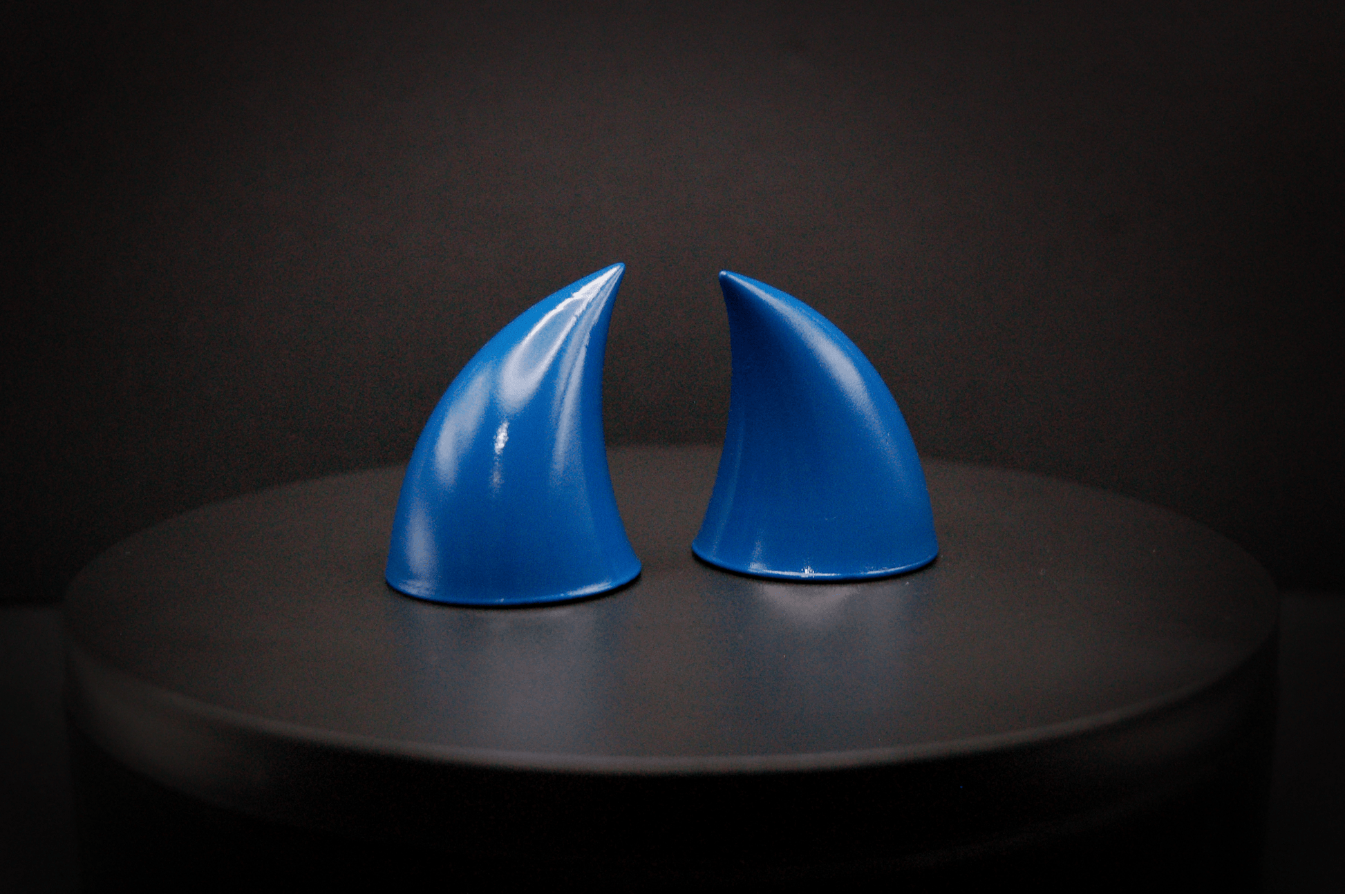 Side view of imp devil horns in storm blue, a deep blue with a glossy finish.