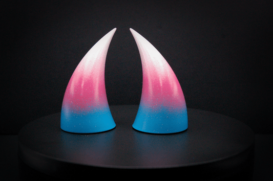 Front view of imp devil horns in a light blue, medium pink, and white ombré, the colors of the trans pride flag with a glittery finish.